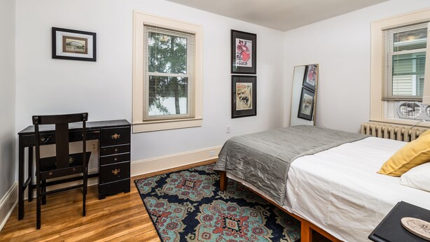 A bedroom with a bed, a desk, and a chair. There are three framed pictures on the wall. - On Johnson Pond _ Near Downtown and SU (Salisbury)