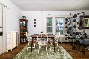 Un comedor con una mesa, sillas, un radiador y un separador decorativo.