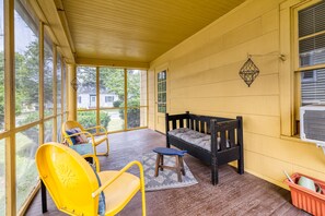 A covered porch with a wooden bench, a yellow chair, and a small table. - On Johnson Pond _ Near Downtown and SU (Salisbury)