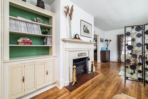 A living room with a fireplace, wooden flooring, a green wall, and a decorative screen. - On Johnson Pond _ Near Downtown and SU (Salisbury)