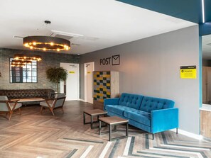 Ein moderner Empfangsbereich mit einem blauen Sofa, einer Holzbank und einem Postschild.