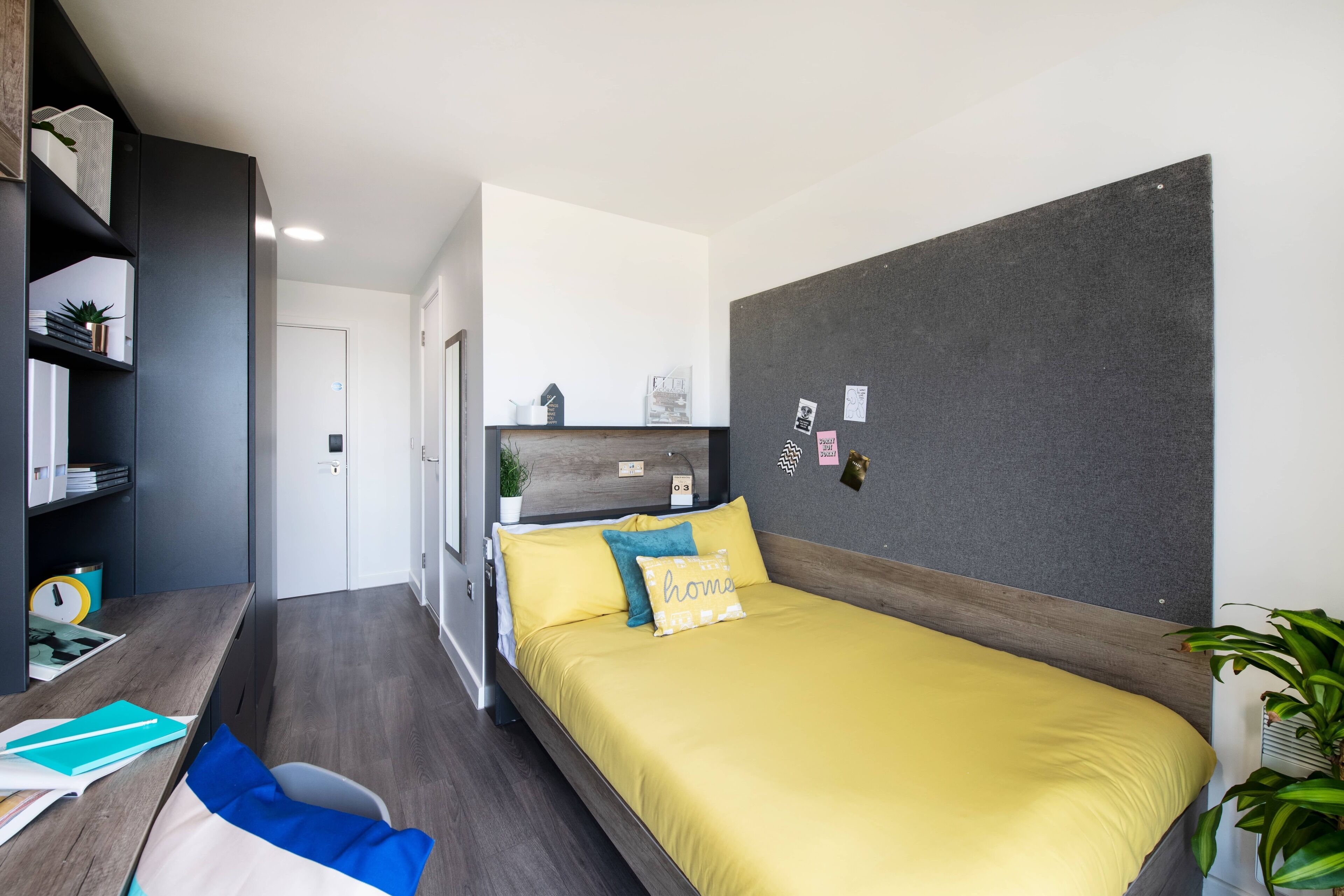 A modern bedroom with a bed, a desk, and a wardrobe.
