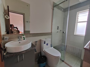 Et badeværelse med håndvask, toilet og brusekabine.