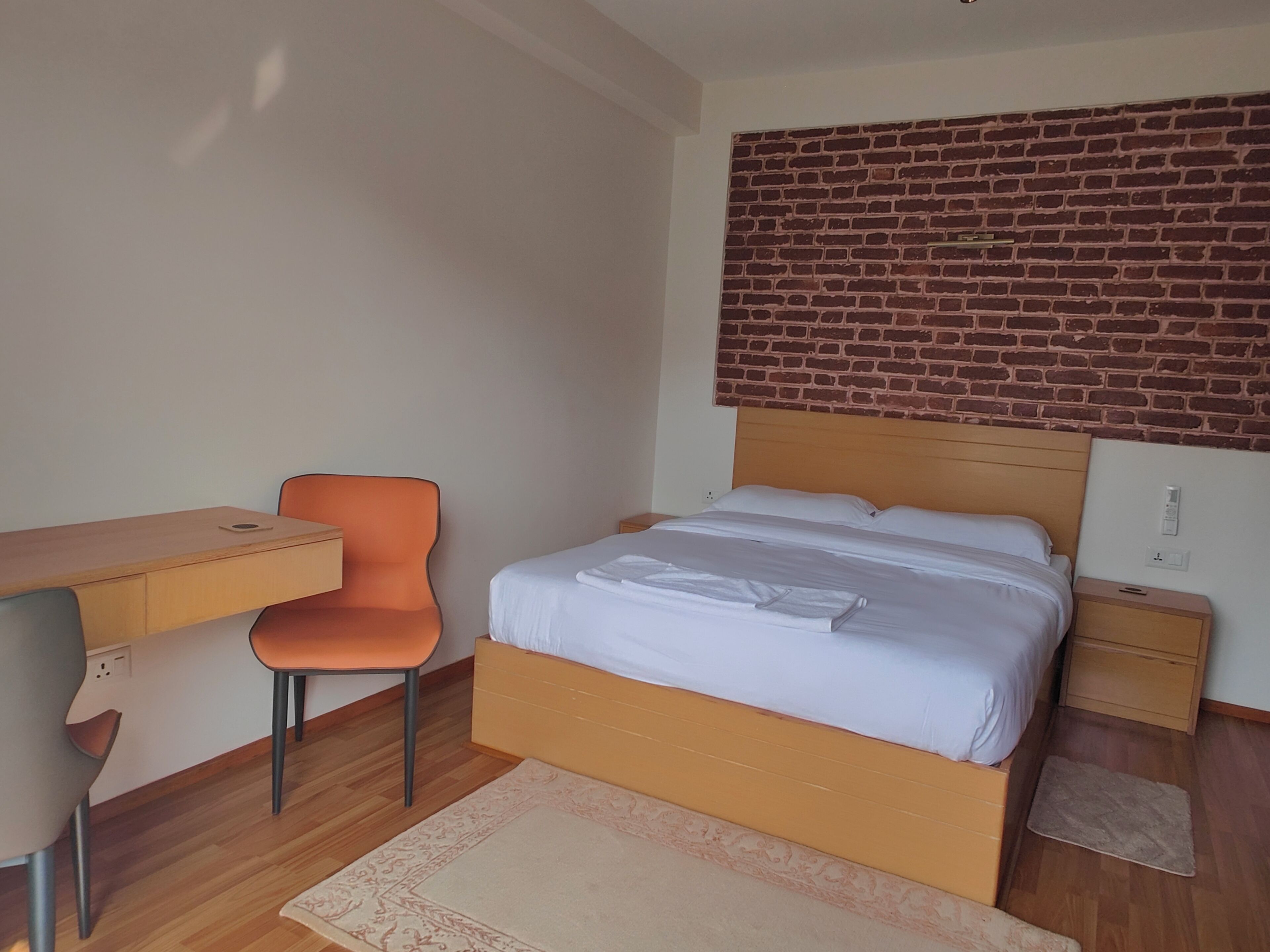A bedroom with a bed, a desk, and a chair.