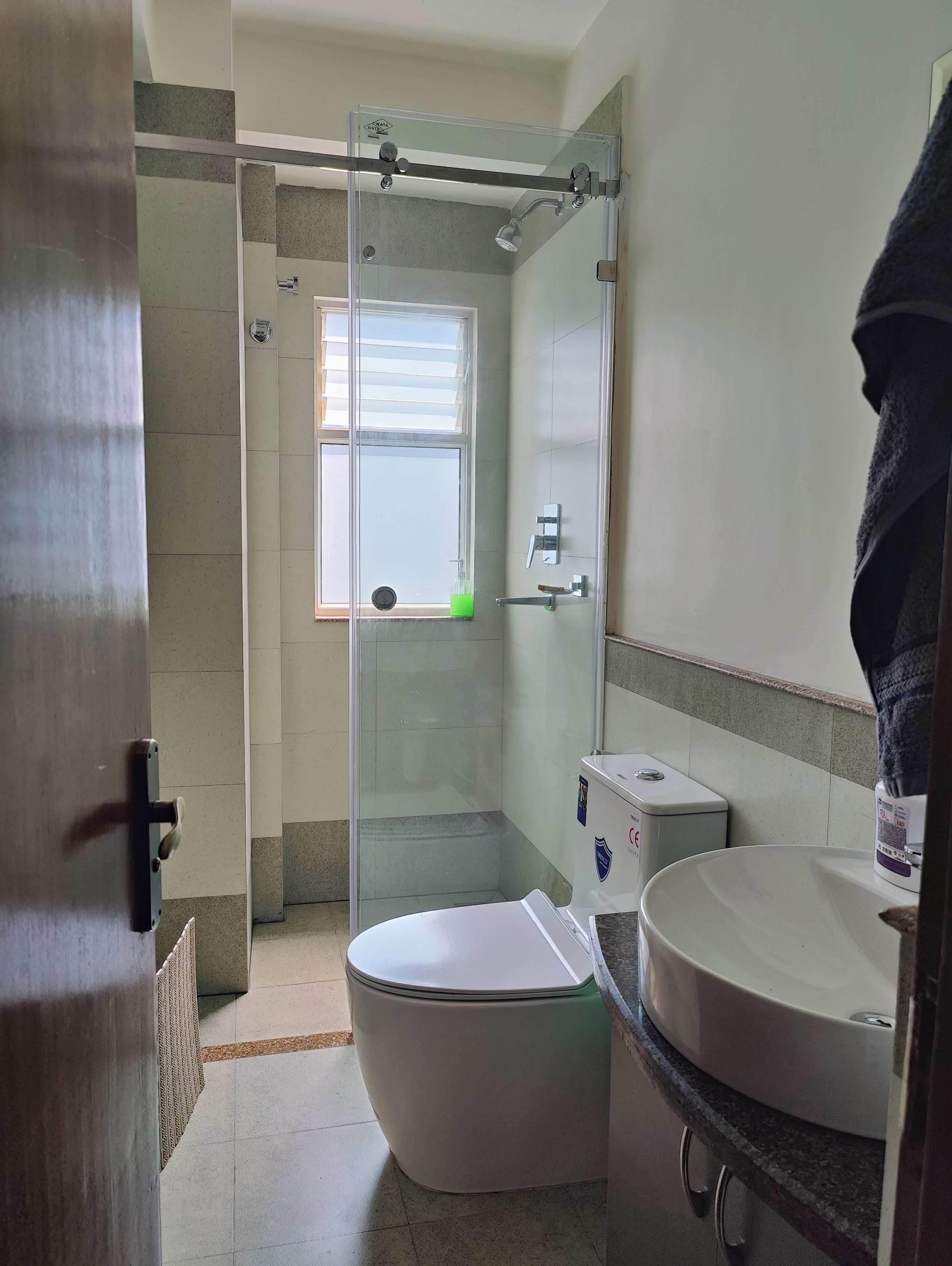 Et badeværelse med bruseniche, toilet og håndvask.