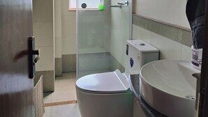 Et badeværelse med bruseniche, toilet og håndvask.