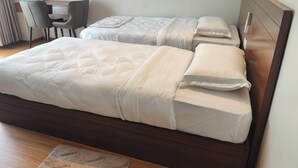 Et værelse med to senge, et skrivebord og en stol.