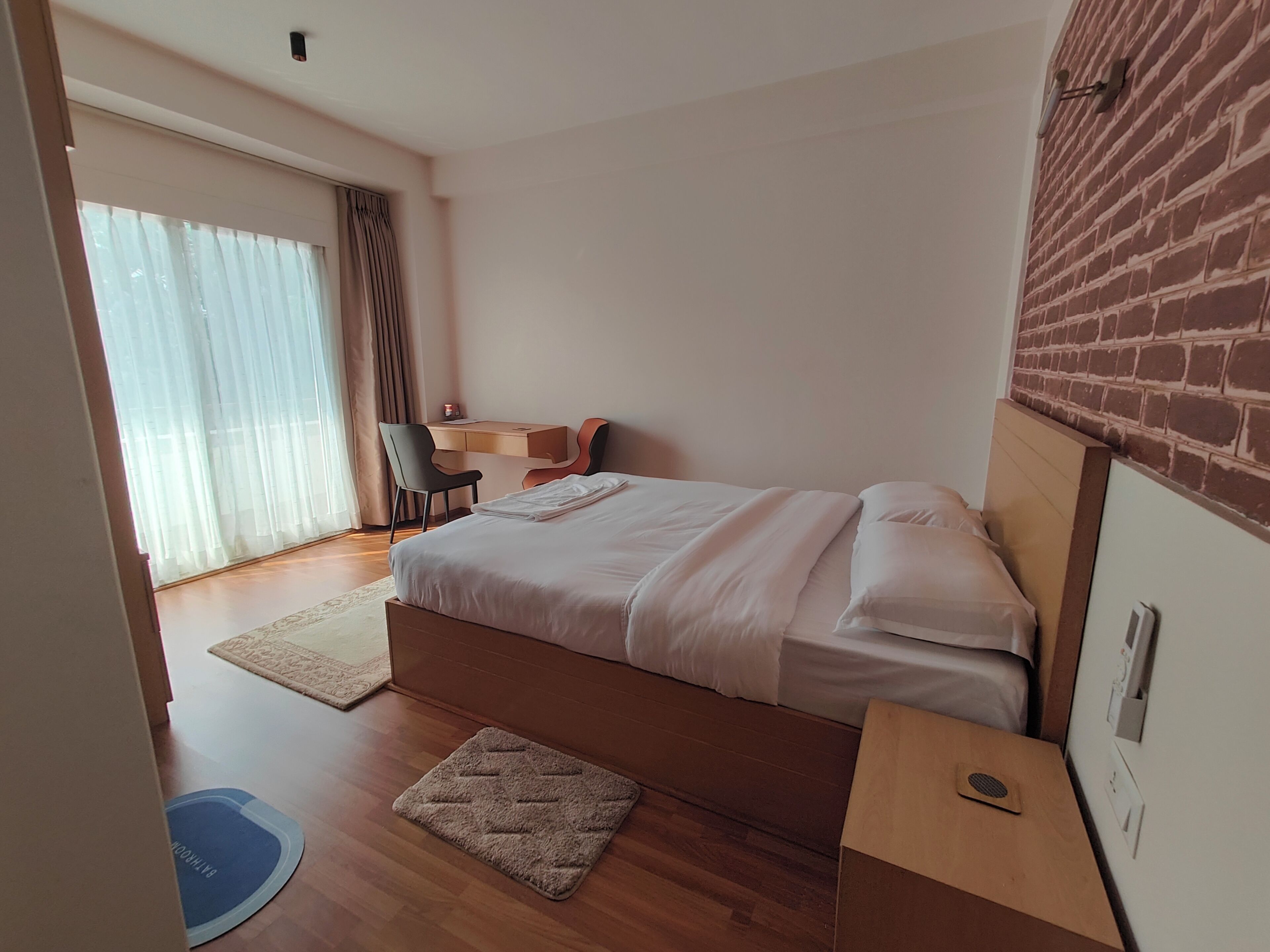 A bedroom with a bed, a desk, and a chair.