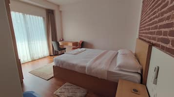 A bedroom with a bed, a desk, and a chair.