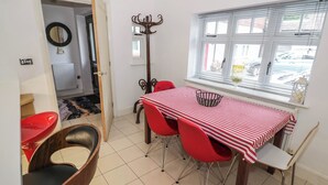 A dining area with a red and white striped tablecloth, red chairs, and a window with blinds. - Tudor Lodge (Birmingham)