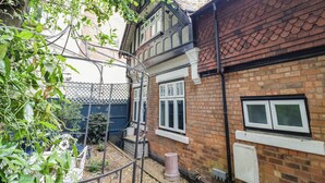 A traditional brick house with a tiled roof, a visible chimney, and a fenced garden area. - Tudor Lodge (Birmingham)
