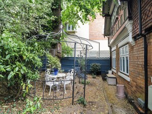 Ein Garten mit einem Metall-Pavillon, einem Tisch und Stühlen.