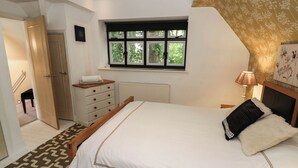 A bedroom with a bed, a dresser, a window, and a door. - Tudor Lodge (Birmingham)