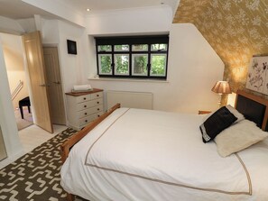 Ein Schlafzimmer mit Bett, Kommode, Fenster und Tür.