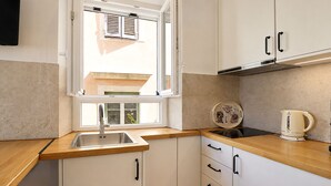 A compact kitchen with a window, a sink, a stove, and cabinets. - Casa Dei Padri #2 - Historic Center (Corfu)