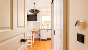 A hallway leading to a kitchen with white cabinetry, a wooden countertop, and a hanging pendant light. - Casa Dei Padri #2 - Historic Center (Corfu)