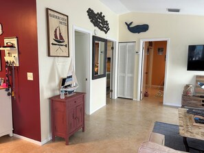 Um quarto com um armário de madeira, um modelo de veleiro, uma decoração de parede com baleia, uma televisão e uma porta que dá para outro quarto.