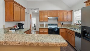 A kitchen with wooden cabinets, granite countertops, a stove, and a refrigerator.