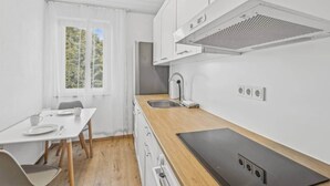 Et moderne køkken med hvide skabe, en træbordplade og et indbygget komfur.