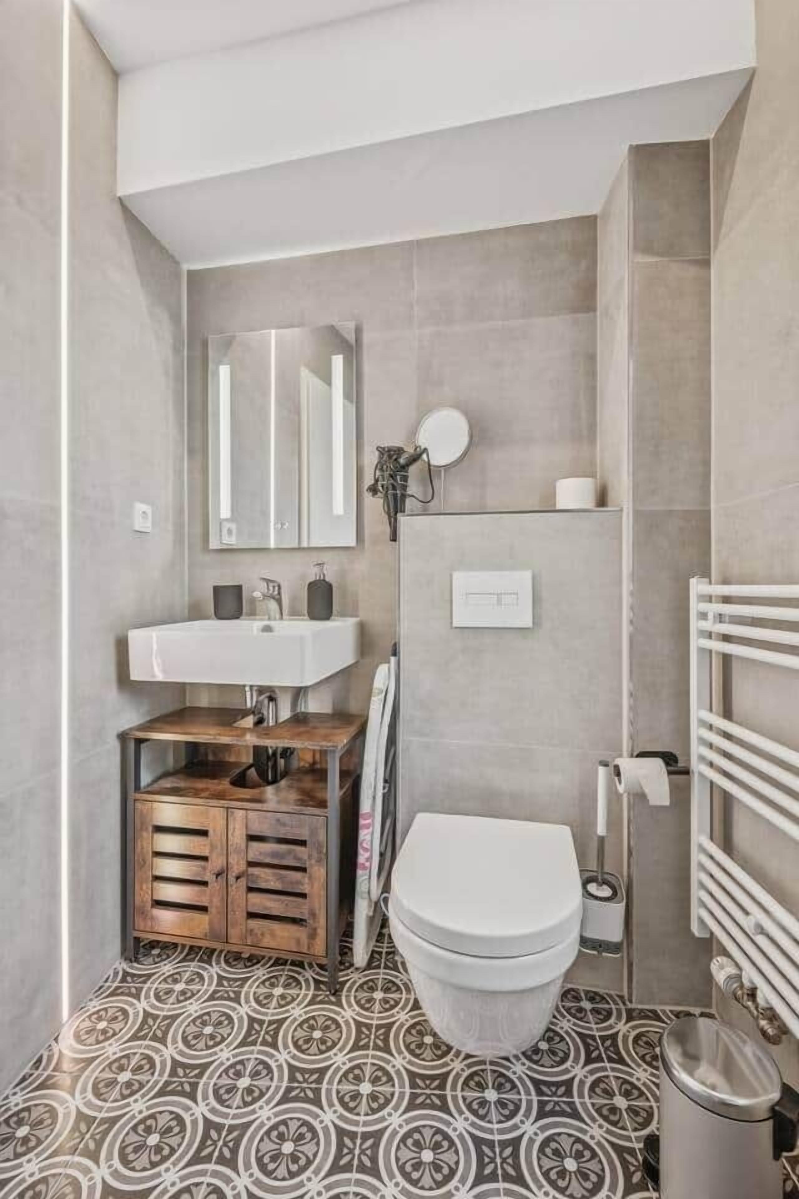 Un bany modern amb un lavabo blanc, un vàter i una zona de dutxa.