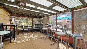 Une terrasse extérieure dotée d’un espace salon couvert, comprenant des tables et des chaises, et offrant une vue sur les environs.