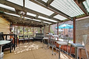 An outdoor patio with a covered seating area, including tables and chairs, and a view of the surrounding area.