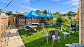 Un jardin avec un espace patio, du mobilier d’extérieur et un coin salon abrité.