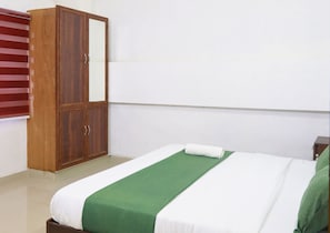 Ein Schlafzimmer mit einem Bett, einem Holzschrank und einem Fenster mit Jalousien.