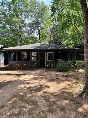 A single-story building with a porch, surrounded by trees.