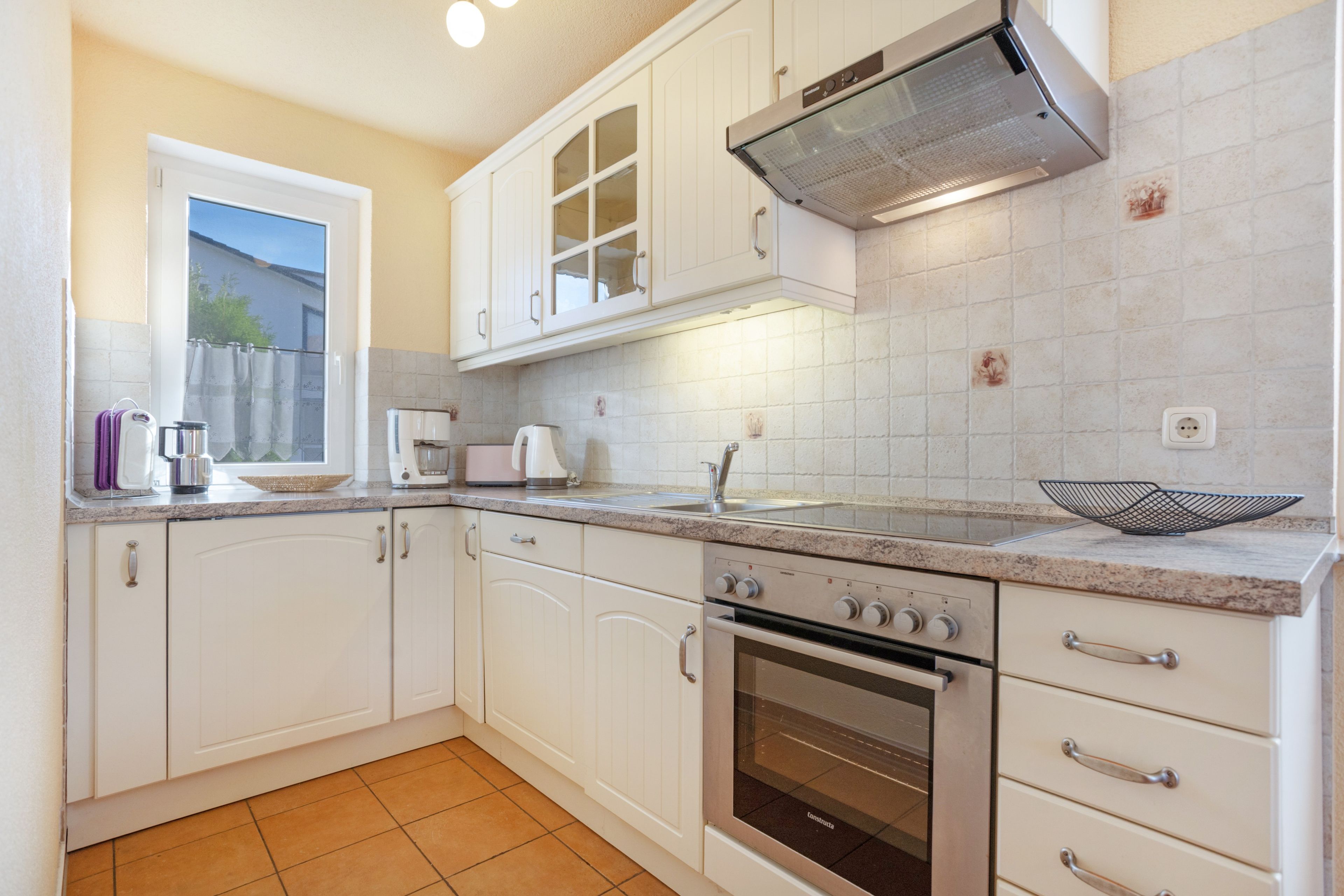 A kitchen with white cabinets, a built-in oven, and a window.