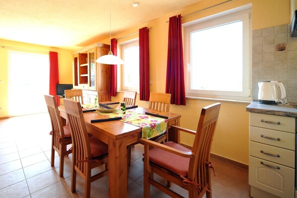 Un comedor con una mesa de madera, sillas y una ventana con cortinas.