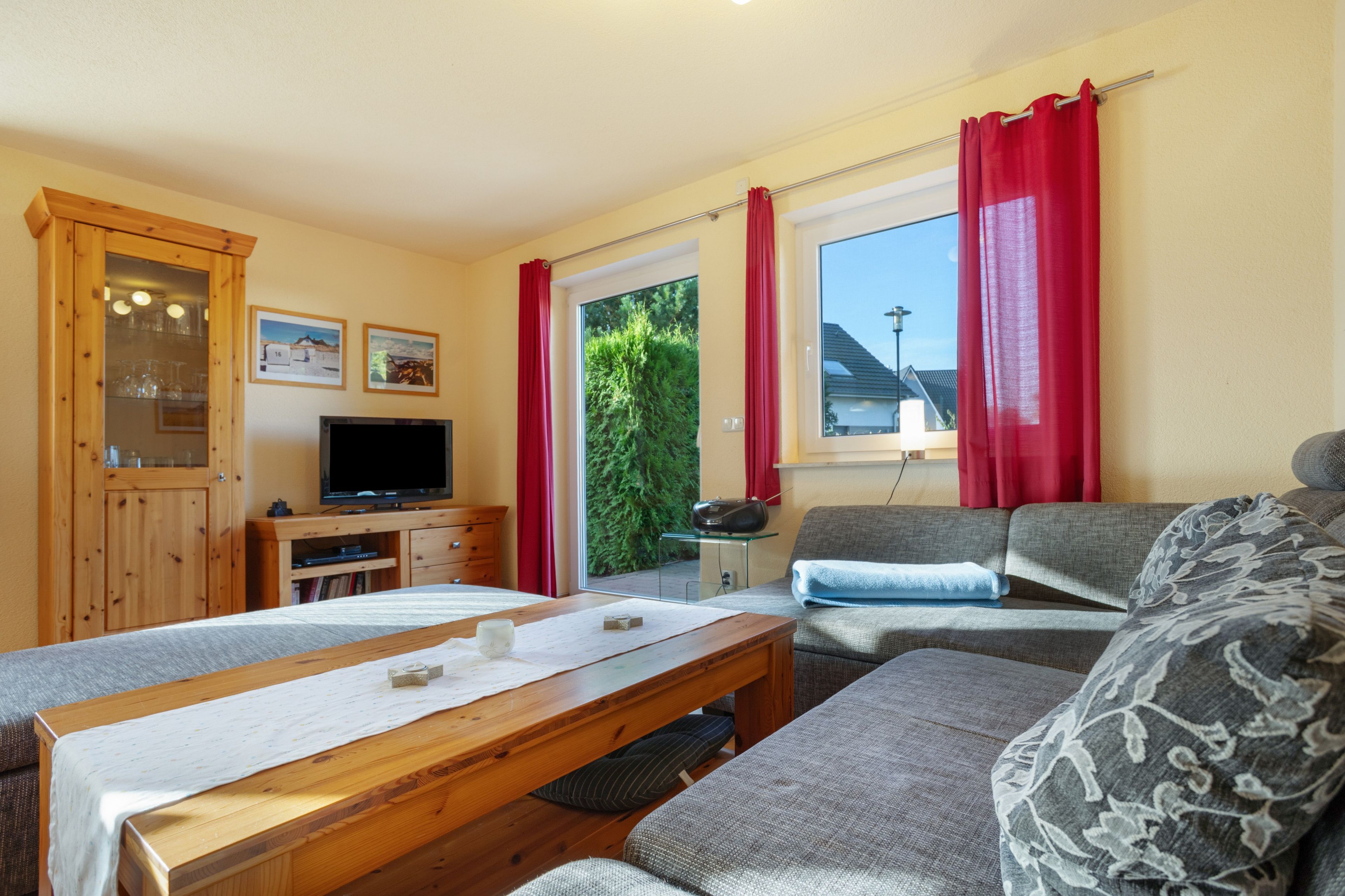A cozy room with a wooden dining table, a sofa, a television, and a cabinet with glass doors.