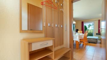 Ein Zimmer mit einem Holzschrank, einem Spiegel und einem Essbereich, der durch einen offenen Durchgang sichtbar ist.