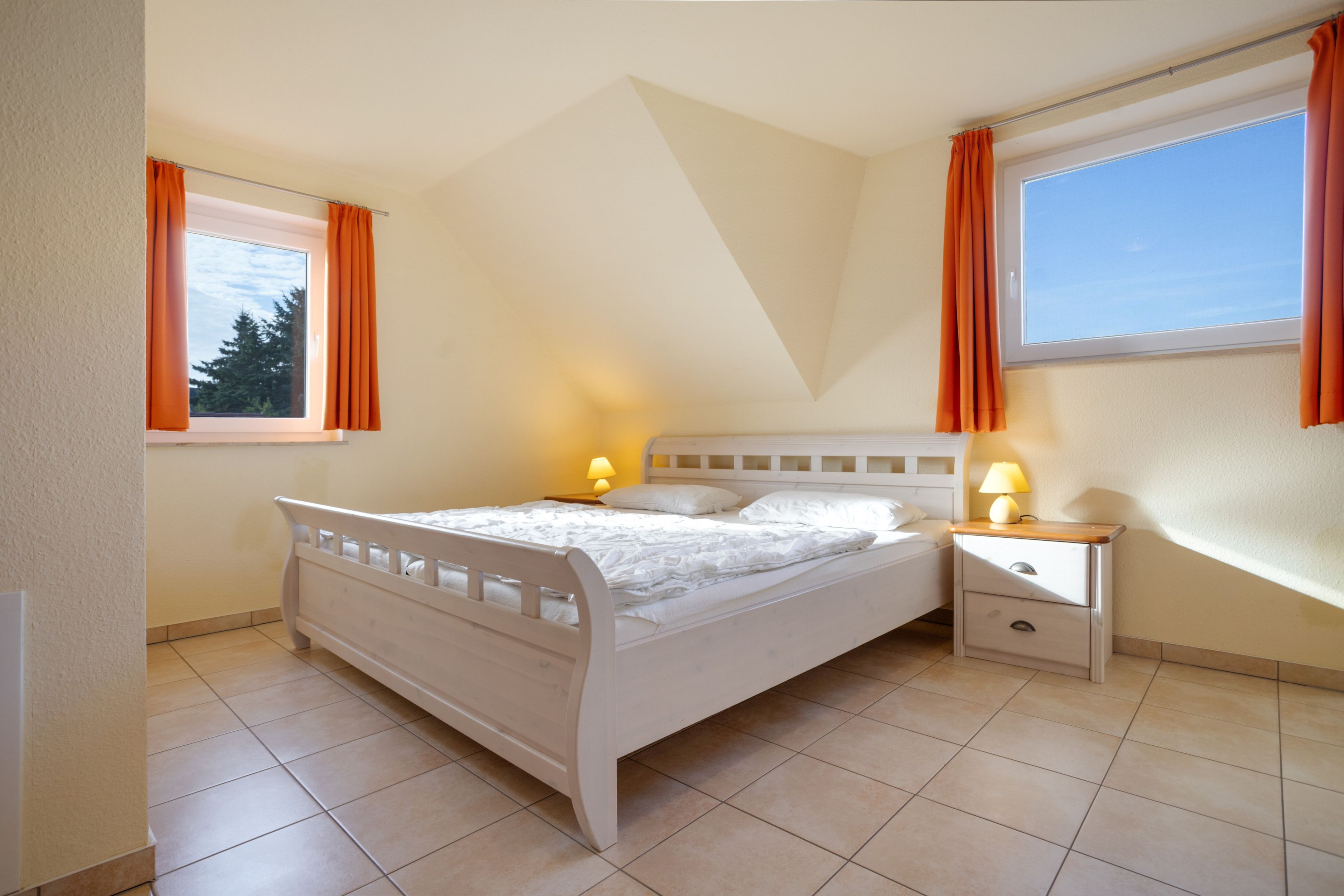 A bedroom with a bed, nightstands, a window, and curtains.
