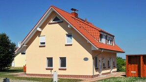 A two-story house with a red-tiled roof, a brick foundation, and a small attached shed. - Hus Utblick in Fuhlendorf (Fuhlendorf)