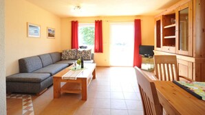 A living room with a sofa, a coffee table, a TV, and wooden cabinets. - Hus Utblick in Fuhlendorf (Fuhlendorf)