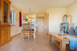 Une cuisine spacieuse avec des meubles de rangement en bois, une table à manger et des chaises. Une fenêtre offre une vue sur l’extérieur.
