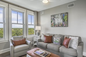 A living room with a sofa, armchairs, a coffee table, and a painting on the wall. - Luxury Baytowne Wharf Condo with Beach and Pool (Miramar Beach)