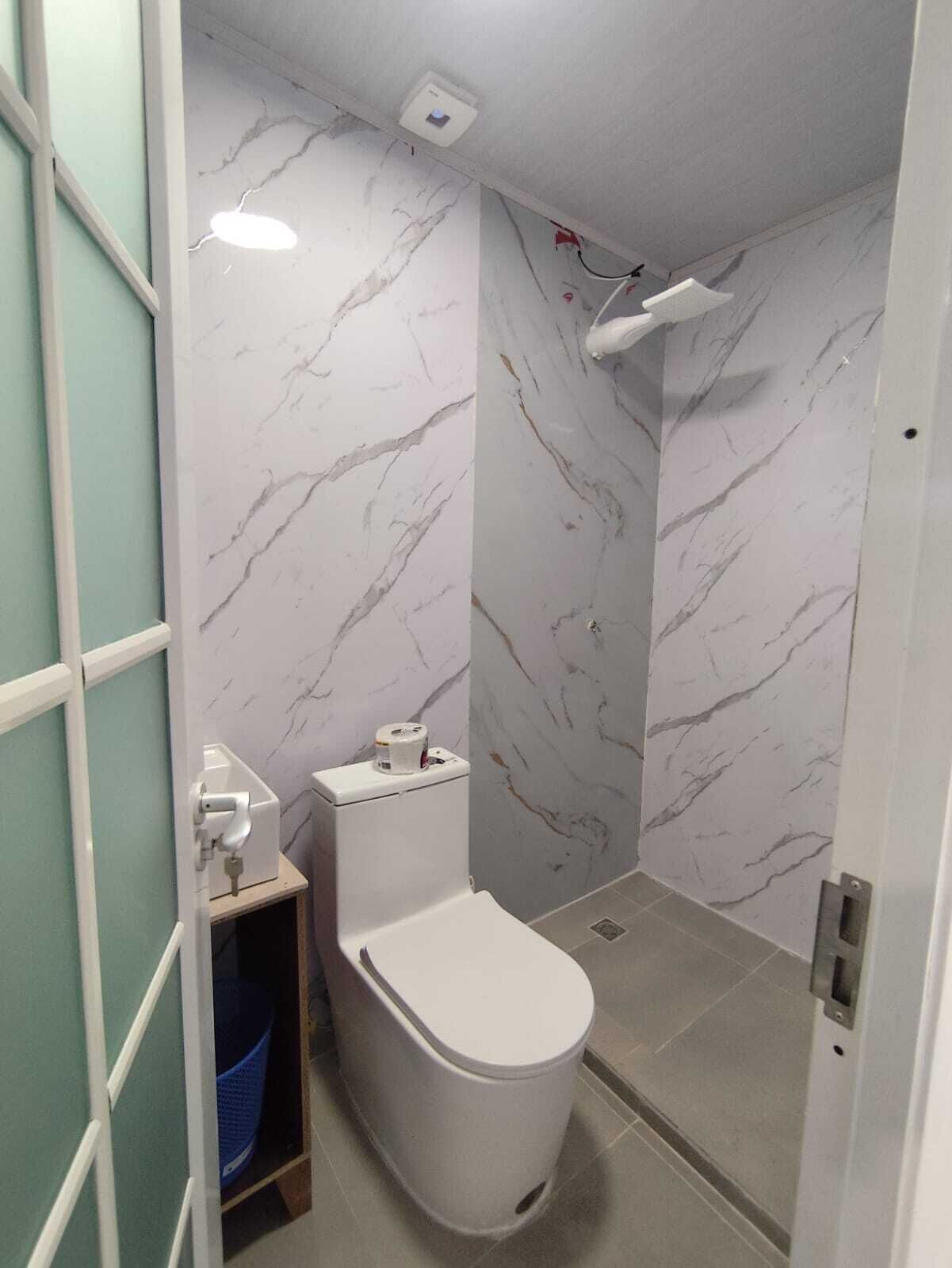 Ein Badezimmer mit Toilette, Dusche und Wand mit Marmoroptik.
