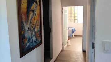 Un pasillo con piso de madera, un cuadro en la pared y una puerta abierta que da a otra habitación.