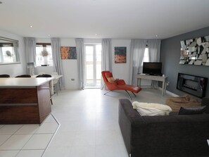 Ein modernes Wohnzimmer mit Essbereich, einer Couch, einem Fernseher und Kunstwerken an den Wänden.