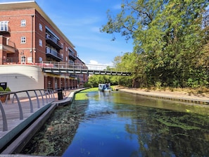 A canal with a bridge, a boat, and a building with balconies. - 63 Vista Heights (Solihull)