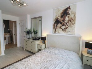 Ein Schlafzimmer mit einem Bett, einem Schminktisch, einem Spiegel und einem Gemälde von einem Pferd.