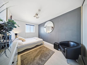 A modern bedroom with a bed, bedside table, mirror, and a black leather chair. - 63 Vista Heights (Solihull)