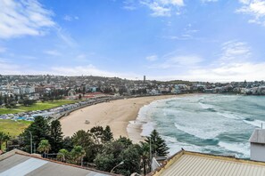 A coastal cityscape with a beach, buildings, and a clear sky. - Golden Sands The Best of Bondi on Your Doorstep (Bondi Beach)