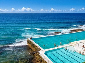 Ein großes Schwimmbecken im Freien mit klarem, blauem Wasser, umgeben von felsigen Klippen und dem Meer.