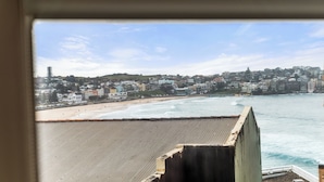 A coastal cityscape with buildings, a beach, and the ocean. - Golden Sands The Best of Bondi on Your Doorstep (Bondi Beach)