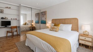 A bedroom with a large bed, bedside tables, a TV, and a desk area. - Golden Sands The Best of Bondi on Your Doorstep (Bondi Beach)