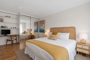 Ein Schlafzimmer mit einem großen Bett, Nachttischen, einem Fernseher und einem Schreibtisch.