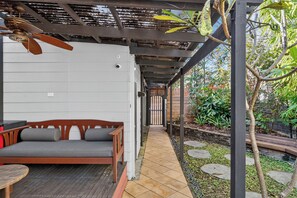 A covered outdoor seating area with a wooden bench and a ceiling fan. - Kingsley Discover Cafs Street Art and Village Life (Newtown)
